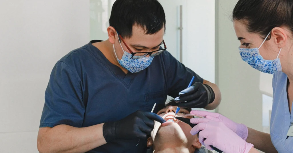 Dental team wearing masks and gloves performing a dental procedure on a patient in a clinic setting
