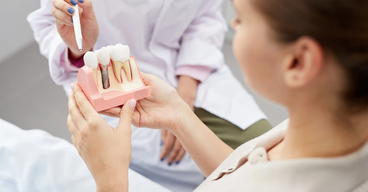 Dentist showing a patient a dental implant model during a consultation